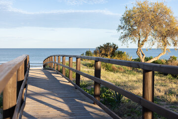 Fototapeta premium Wooden pier at sunset along the dune beach.