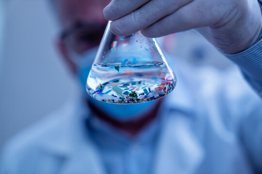 Scientist examining microplastic particles in a laboratory flask, studying environmental contamination