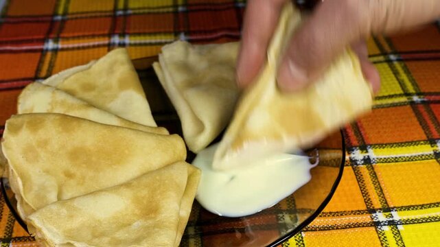 A man dips a pancake into condensed milk. 4K video