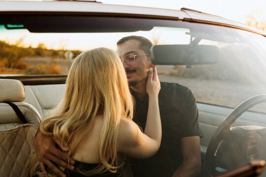 couple embracing in classic convertible car