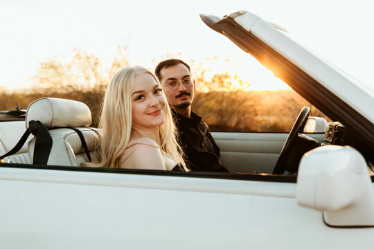 couple in parked convertible car during sunset