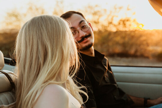 couple looking at each other in a parked convertible car