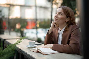 Obraz premium Woman dreaming on cafe terrace thinking about future