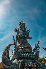 Fototapeta premium Statue Wat Rong Seur Ten (Blue Temple), Chiang Rai against the sky