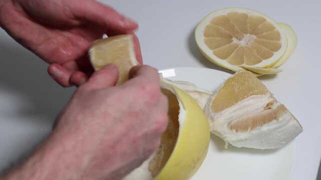 Close-up of hands peeling sweet and juicy pomelo fruit, emphasizing healthy eating and citrus fruit concepts for food and drink visuals, ideal for fresh food themes.