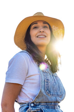 Woman farmer wearing straw hat and overalls, smiling, looking at sun rays. PNG