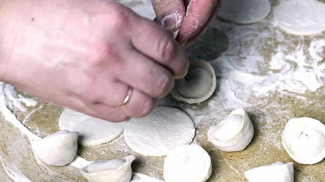 The housewife is making dumplings by putting meat into the dough. Video