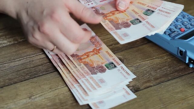 Person counting ruble banknotes on his hands.