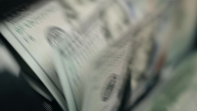 High-speed counting of one hundred dollar bills in money counter. Accounting concept.
