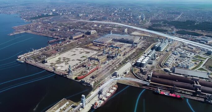 The process of building or repairing a large ship in a dry dock at a shipyard. Smart factory. Shipbuilding at a shipyard. A large ship is being built in a dry dock at the shipyard. Aerial view.