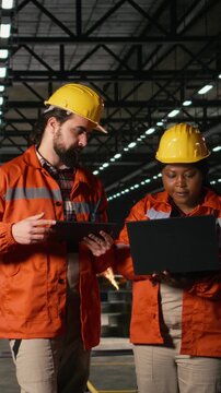 Vertical Video Diverse engineers coordinate operations across heavy industry production line, engineering plant. Overseeing operations with heavy equipment and industrial design for manufacturing