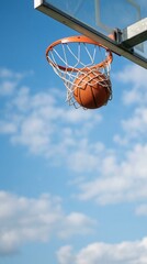 Naklejka premium Outdoor Basketball Hoop and Net with Ball against Blue Sky and Clouds