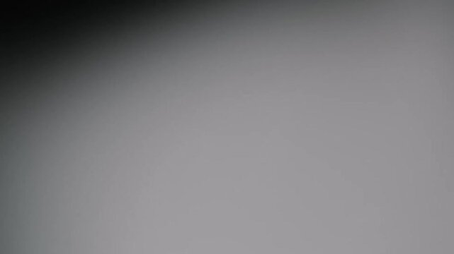 Abstract dark grey light leak gradient subtly shifting and glowing in a moody cinematic space featuring soft out of focus transitions and bokeh textures