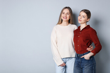 Fototapeta premium Mother and her teenage daughter on light grey background, space for text