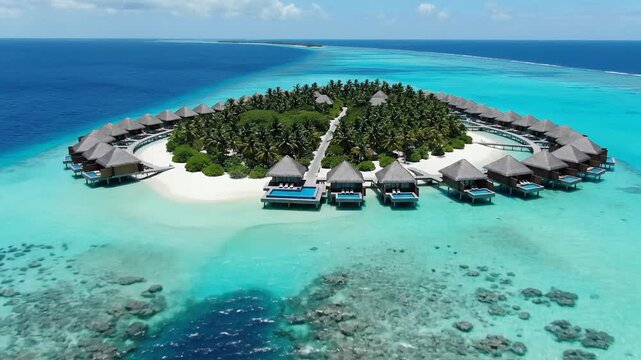 Aerial drone view of luxury overwater bungalows on a tropical island resort in turquoise lagoon