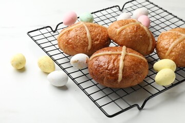 Hot cross buns and decorated eggs on white table, closeup