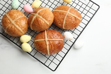 Hot cross buns and decorated eggs on white table, flat lay