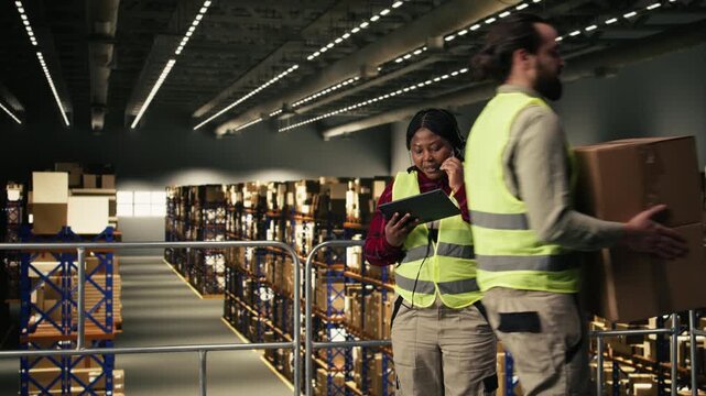 Black woman, staff assisting customers, order fulfillment, delivery status, verifying AWB and shipment details on tablet. Managing customer service complaints on headset, logistics facility.