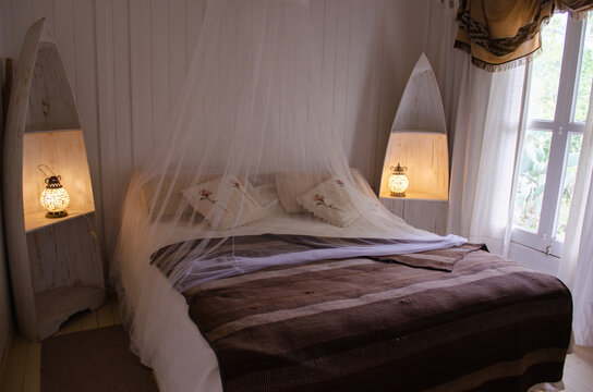 Cozy  white room with bed net and rustic wood.