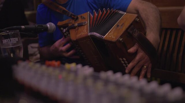 Accordion concertina musician plays music near audio  mixing desk