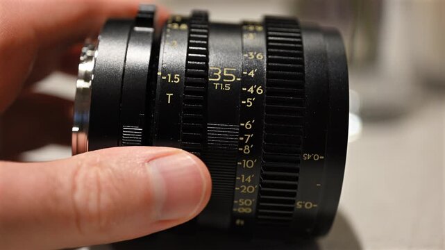 Close up of professional camera lens with aperture and focus rings being adjusted by hand