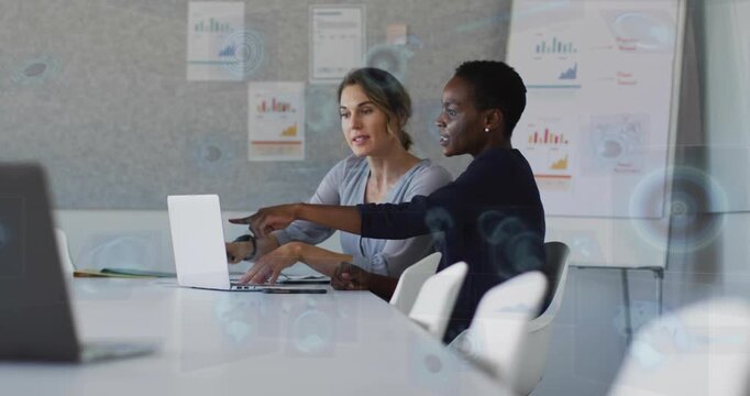 Mentor pointing at laptop, colleague typing and guiding with business charts, finalizing report
