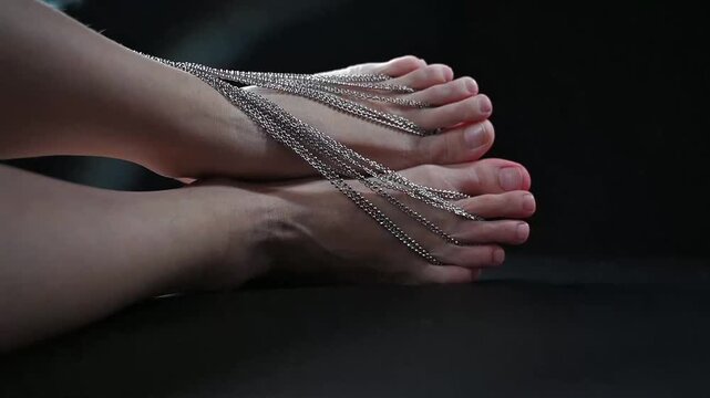Foot fetish. Close-ups of naked female feet with silver chain jewelry.