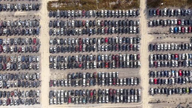 Aerial top down view of many damaged cars stored in a large parking lot