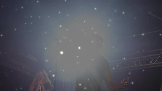 Male lead singer gripping mic and singing in live music show, causing sparkle haze intensifying