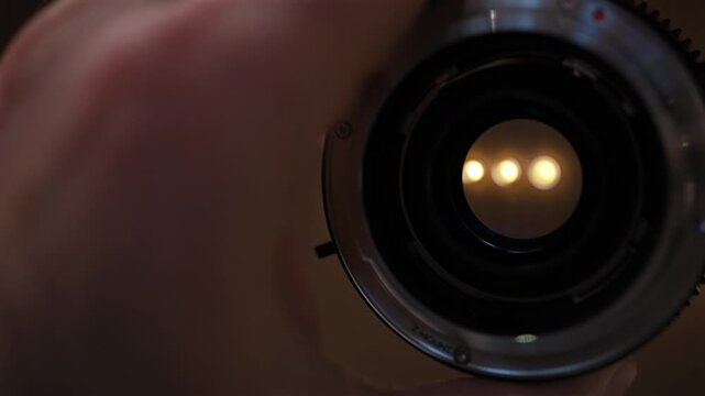 Close up view through the rear side of a camera lens with light reflections in the glass
