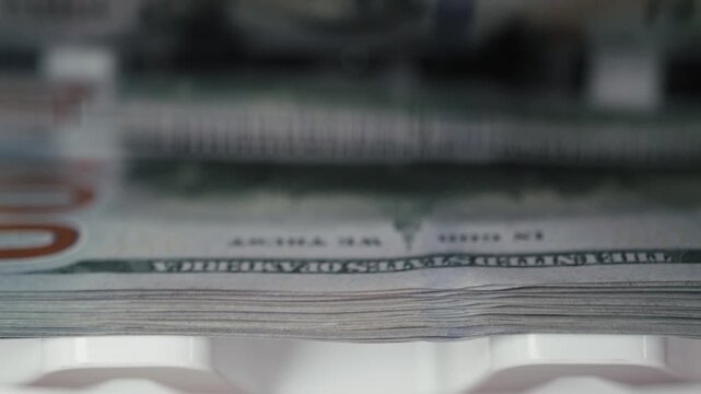 Close-up view of stacked banknotes being processed in a currency counting machine, showcasing the continuous flow of cash in a financial setting