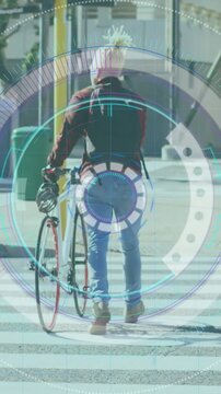 Vertical video: Male commuter stepping from curb, crossing crosswalk, pushing bike under HUD
