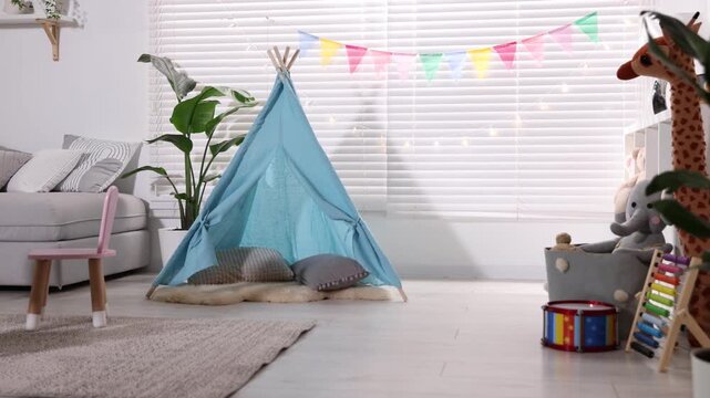 Child's room with furniture, toy wigwam, toys, colorful flags and decorative lights. Camera moving forward