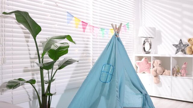 Child's room with toy wigwam, houseplant, toys and colorful flags. Camera moving forward