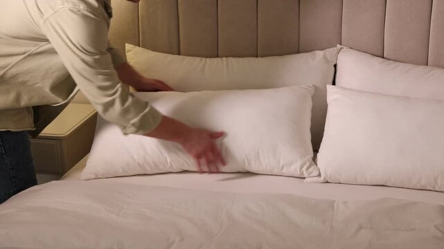 Man putting pillow onto bed at home, closeup