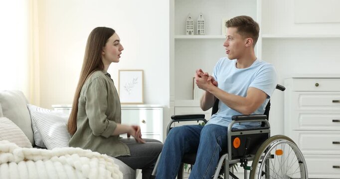 Man in wheelchair talking with woman at home