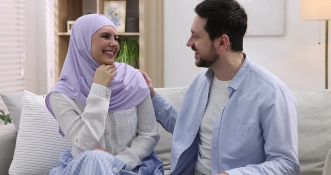 Happy muslim couple talking on sofa at home