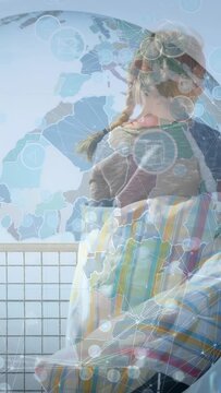 Vertical video: Girls entering wrapping blanket starting globe overlay for tech demo at ocean rail