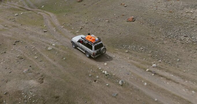SUV Car Traveling Across Terrain Through Tsagaan Gol Valley In The Altai Mountains Of Mongolia. Aerial Tracking Shot