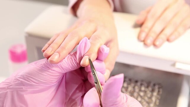 Professional manicurist cutting client's cuticle in beauty salon, closeup