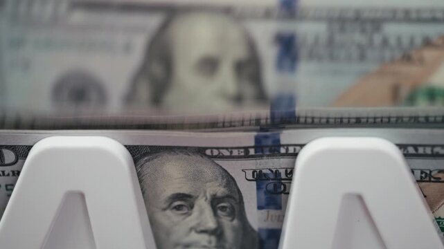 Close-up of stacked U.S. dollar bills with a white money holder displaying the face of Benjamin Franklin in a well-lit financial setting