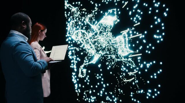 Team of AI startup data scientists implement deep learning algorithms with laptop, collaborating. Coworkers coding, modifying artificial intelligence neural network architecture with device, camera A