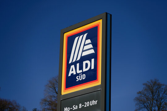 Hellenthal, Germany March 18 2026: Exterior logo sign of a German Aldi S&uuml;d discount supermarket with opening hours. Set against a clear blue sky on a sunny day