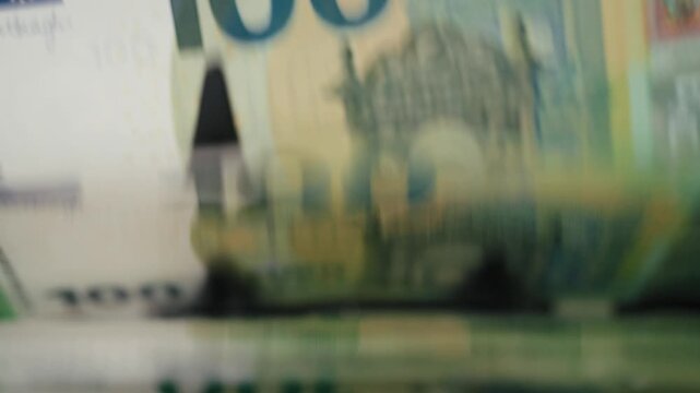 Close-up of &euro;100 bills in electronic counting machine with digital display. Finance concept.
