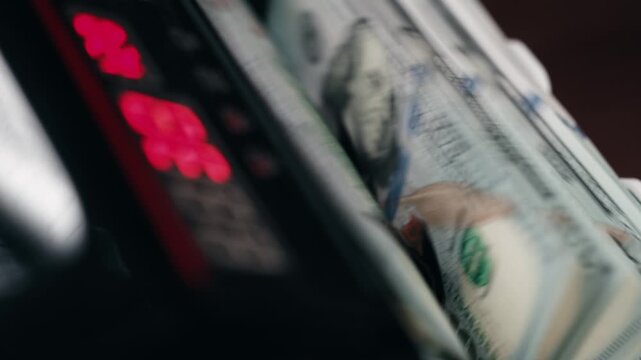 Close-up of $100 bills processed in money counting machine. Cash handling concept.
