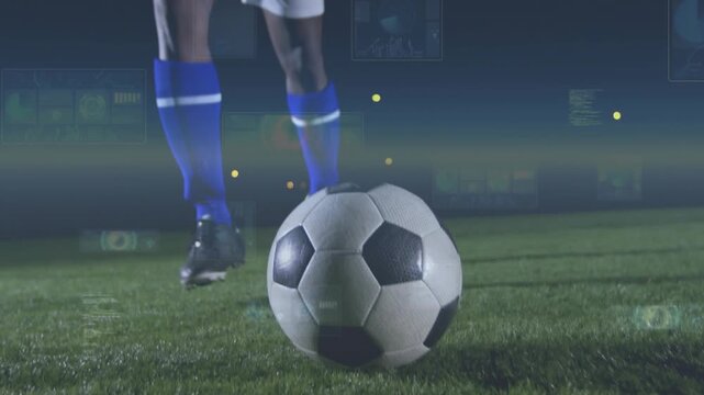 Shifting, male player wearing blue jersey kicking ball to push forward on night pitch with HUD
