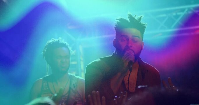 Music starting, lead singer singing into mic, leaning, gesturing toward crowd while lights sweeping