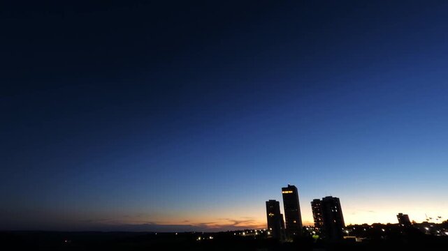Time-lapse video capturing sunset transitioning into night over an urban skyline in Brazil, highlighting changing light conditions, sky colors, and the gradual activation of city lights