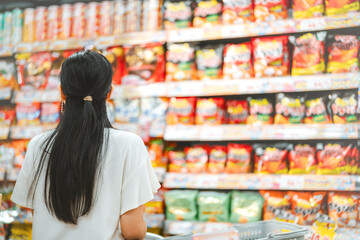 Rear view young adult asian woman customer choosing snack food from shelf shopping at asia supermarket © dodotone
