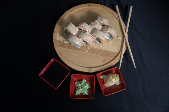 Sushi roll with salmon, cheese and avocado. Maki roll with shrimps fried, avocado and lattuce on a wooden plate . Delicious sushi rolls served on grey table